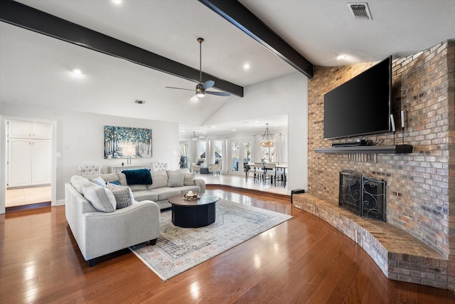 living area with vaulted ceiling with beams, visible vents, and wood finished floors