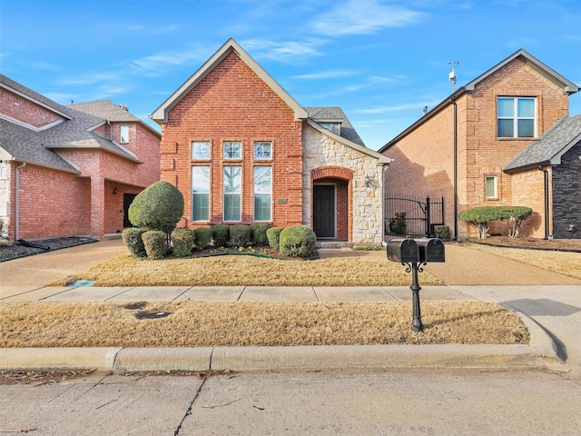 view of front of property featuring stone siding, a gate, and brick siding