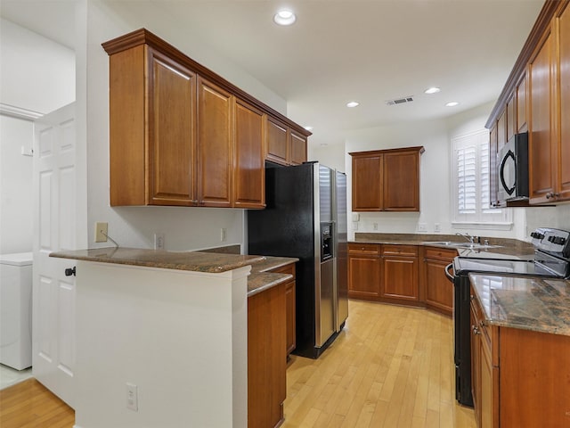 kitchen featuring a peninsula, light wood-type flooring, black microwave, and electric range oven