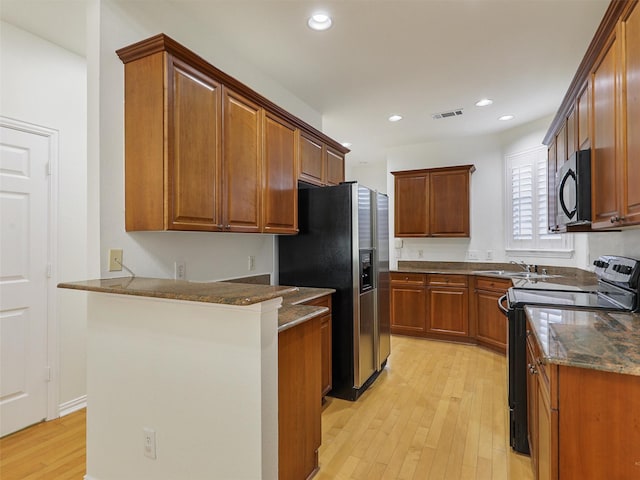 kitchen with black microwave, light wood-style flooring, a peninsula, electric stove, and stainless steel refrigerator with ice dispenser