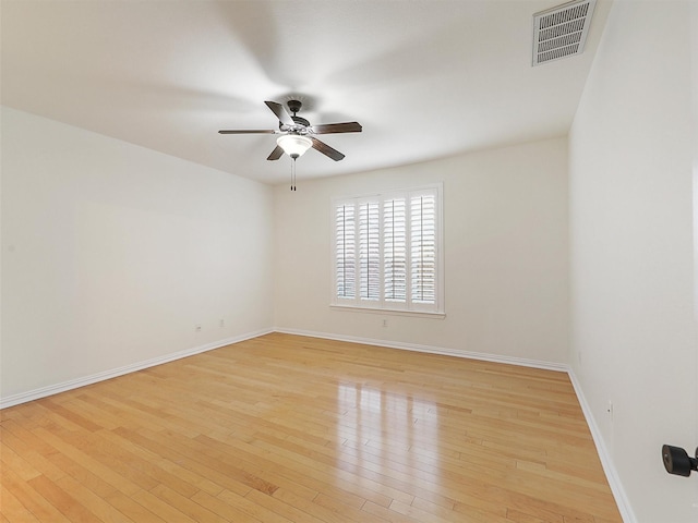 empty room with a ceiling fan, visible vents, light wood-style flooring, and baseboards