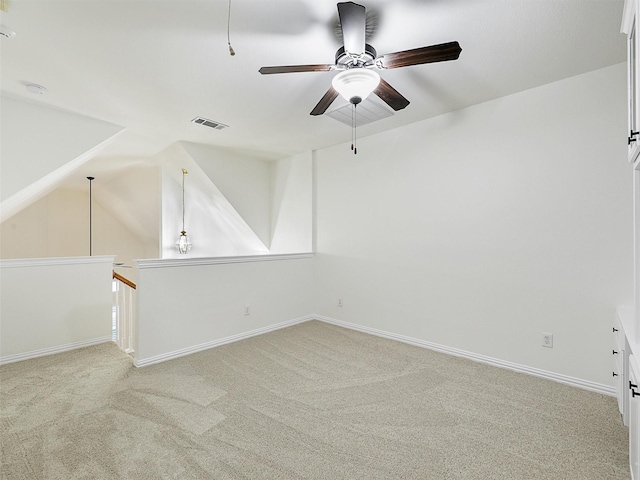 spare room featuring visible vents, light carpet, vaulted ceiling, ceiling fan, and baseboards