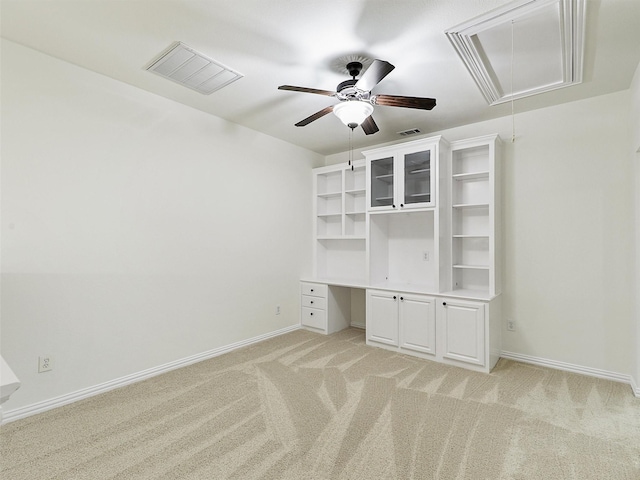 unfurnished bedroom featuring attic access, visible vents, built in desk, and light carpet