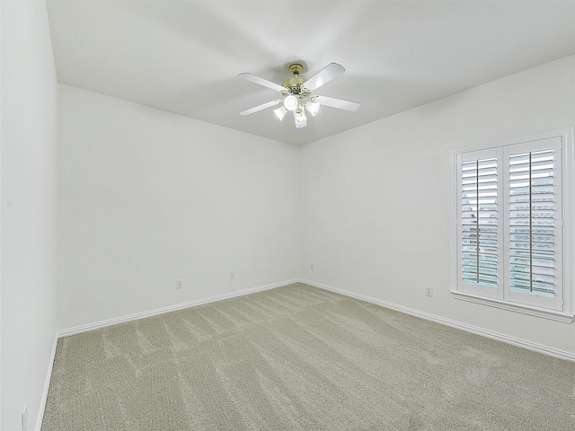 spare room with light carpet, ceiling fan, and baseboards