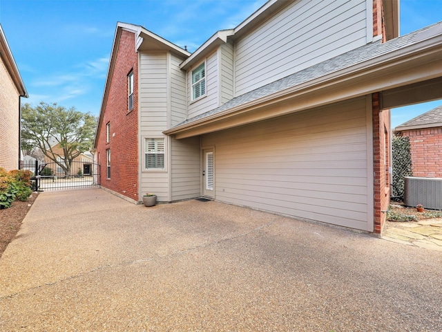 back of house featuring a patio area, brick siding, fence, and a gate