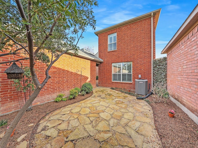 rear view of property with central AC, brick siding, and a patio area