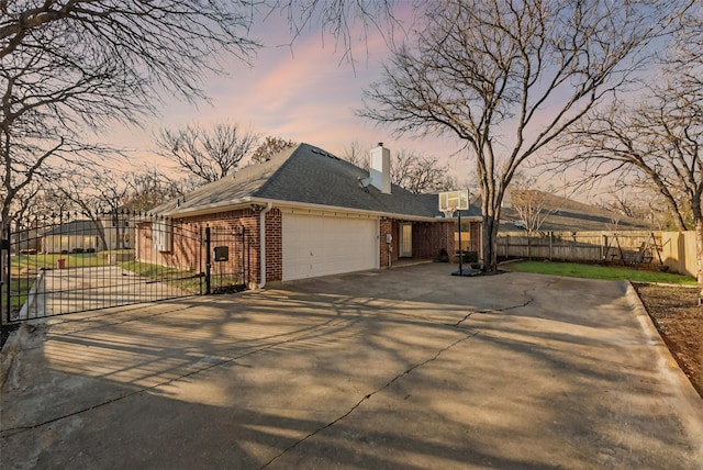 view of home's exterior with a garage, brick siding, fence, concrete driveway, and a gate