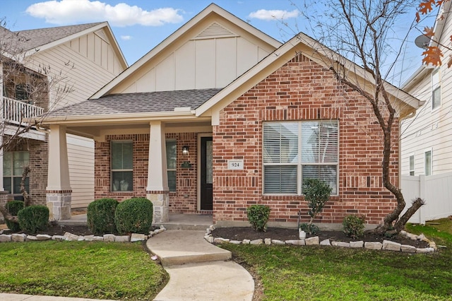 view of front of house featuring a porch, fence, board and batten siding, a shingled roof, and brick siding