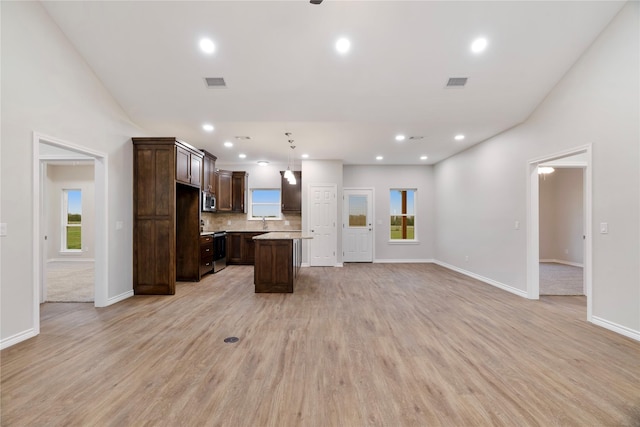 kitchen with open floor plan, stainless steel appliances, visible vents, and dark brown cabinetry