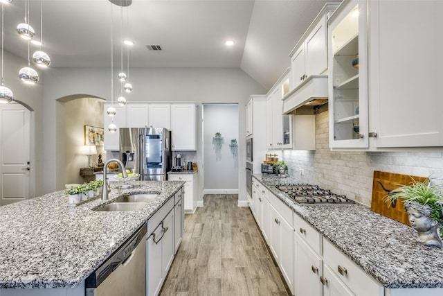 kitchen featuring light wood-type flooring, backsplash, stainless steel appliances, and a sink