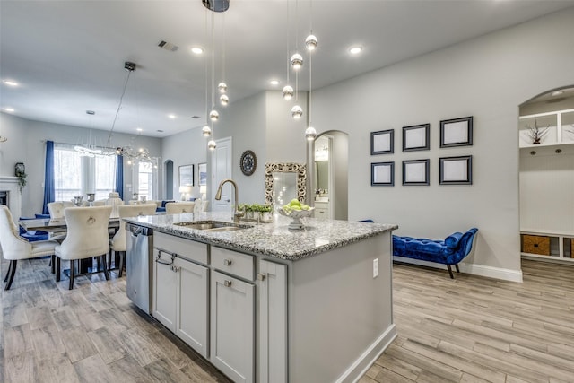 kitchen with arched walkways, visible vents, stainless steel dishwasher, open floor plan, and a sink