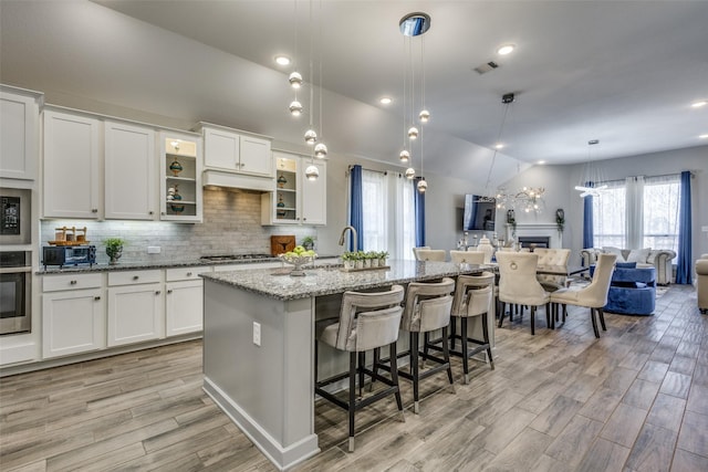 kitchen with visible vents, light stone counters, stainless steel appliances, vaulted ceiling, and backsplash