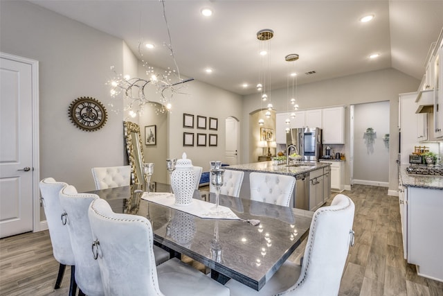 dining space featuring arched walkways, recessed lighting, visible vents, vaulted ceiling, and wood finished floors