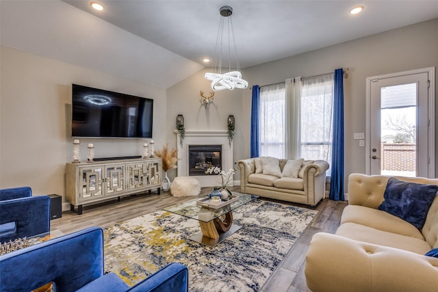 living room featuring recessed lighting, a glass covered fireplace, vaulted ceiling, wood finished floors, and baseboards