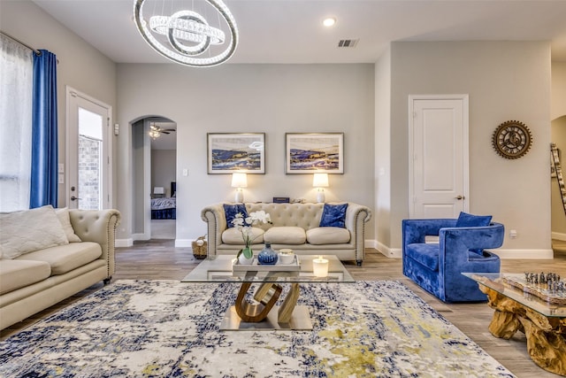 living area with arched walkways, visible vents, baseboards, and wood finished floors