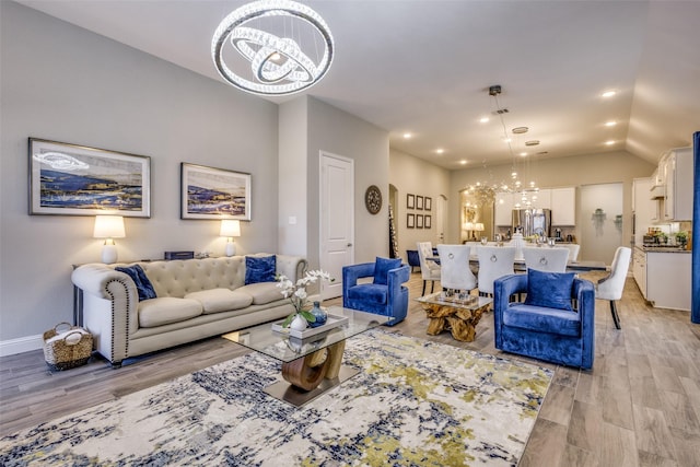 living room featuring baseboards, vaulted ceiling, light wood-style floors, a notable chandelier, and recessed lighting