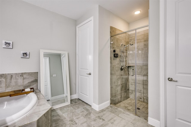 bathroom featuring a stall shower, baseboards, and a bath