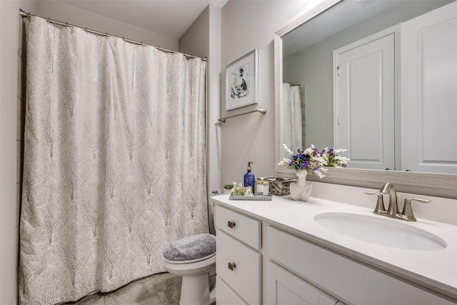 full bathroom featuring tile patterned flooring, a textured wall, vanity, and toilet