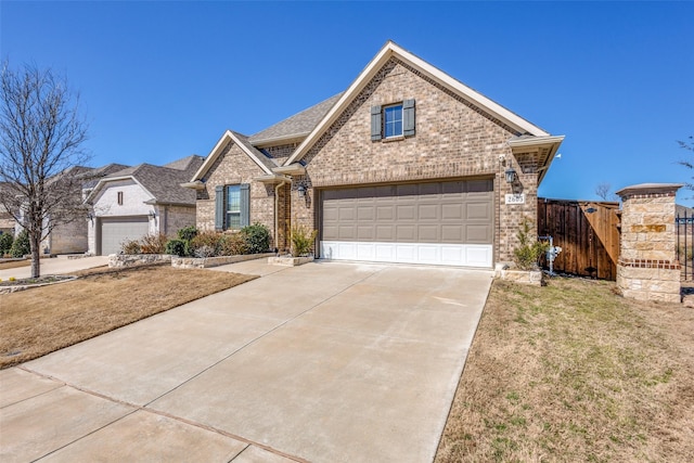 view of front facade with a garage, brick siding, driveway, and fence