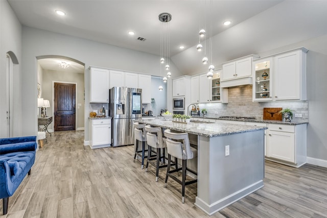 kitchen with visible vents, arched walkways, appliances with stainless steel finishes, a sink, and backsplash