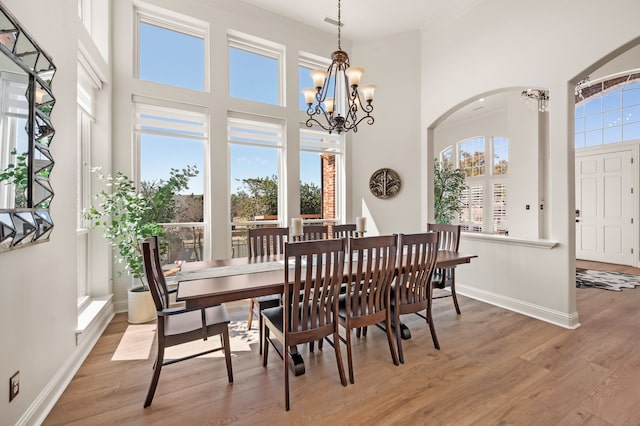 1503 Kingswood Ln, Colleyville, TX 76034 - dining room with light wood-type flooring, arched walkways, a chandelier, a high ceiling, and baseboards