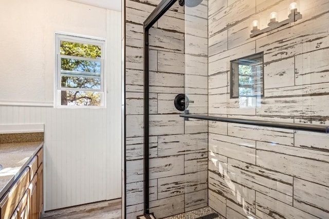 full bath with vanity, a stall shower, a wainscoted wall, wood walls, and wood finished floors