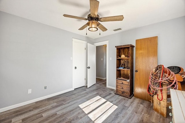 unfurnished bedroom featuring visible vents, baseboards, a ceiling fan, and wood finished floors