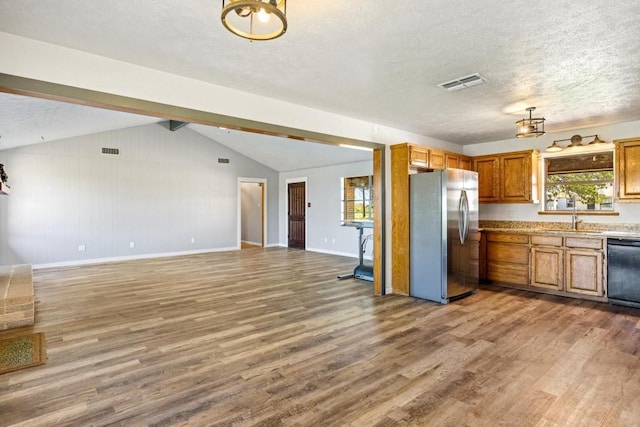 kitchen featuring freestanding refrigerator, visible vents, wood finished floors, dishwasher, and a sink