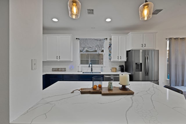 kitchen with appliances with stainless steel finishes, a sink, visible vents, and decorative backsplash