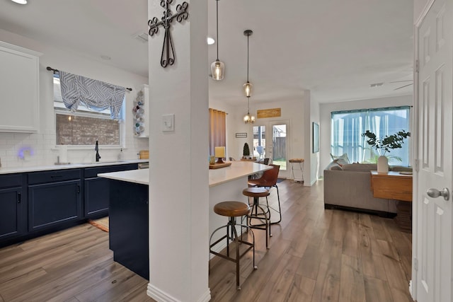 kitchen featuring light wood-type flooring, a sink, backsplash, and a kitchen breakfast bar