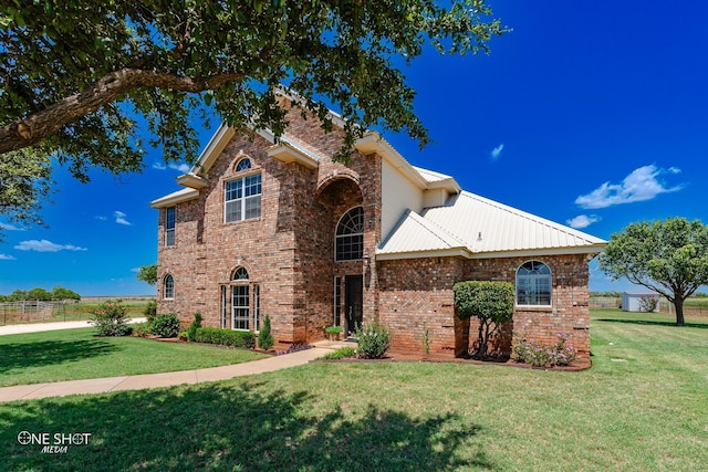 traditional-style house with a front yard, metal roof, and brick siding