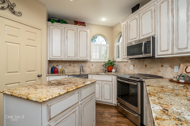 kitchen featuring tasteful backsplash, dark wood finished floors, appliances with stainless steel finishes, light stone counters, and recessed lighting