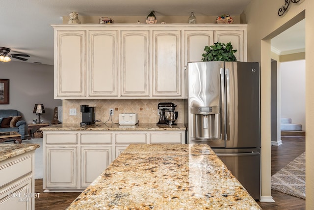 kitchen with decorative backsplash, a ceiling fan, dark wood-style flooring, light stone countertops, and stainless steel refrigerator with ice dispenser