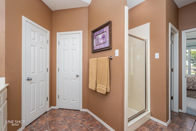 ensuite bathroom featuring ensuite bath, a shower stall, and baseboards