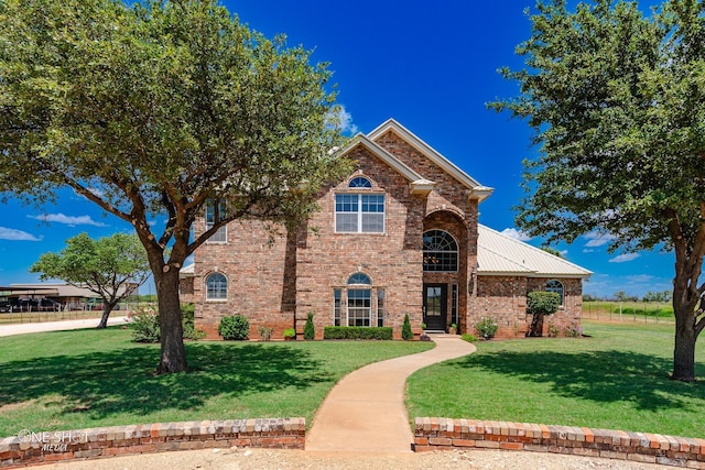 traditional-style house featuring a front yard, metal roof, and brick siding