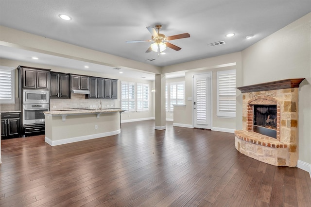 unfurnished living room with dark wood-type flooring, a fireplace, and baseboards