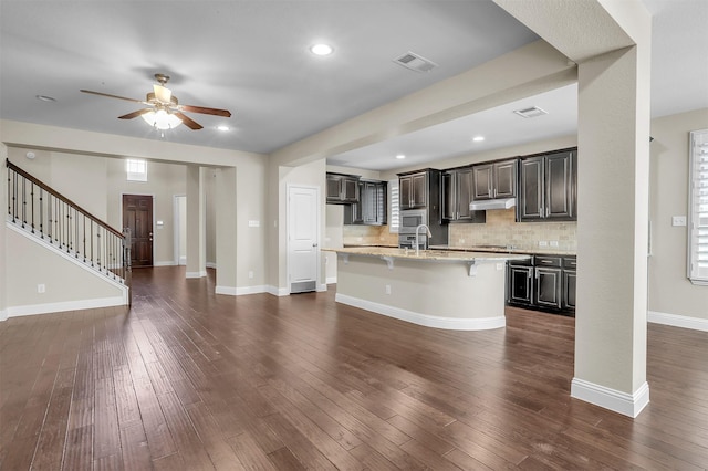 kitchen featuring dark wood-style floors, stainless steel microwave, a sink, and under cabinet range hood