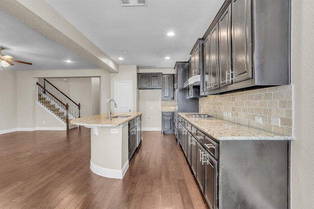 kitchen with dark wood finished floors, a sink, backsplash, and light stone countertops