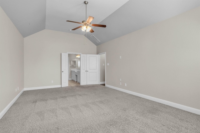 unfurnished bedroom featuring lofted ceiling, light carpet, ceiling fan, ensuite bath, and baseboards