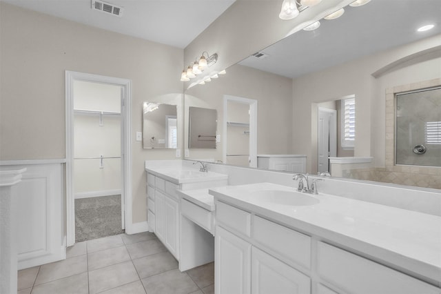 full bathroom featuring visible vents, a spacious closet, a tile shower, vanity, and tile patterned flooring