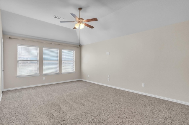 carpeted spare room with ceiling fan, visible vents, vaulted ceiling, and baseboards