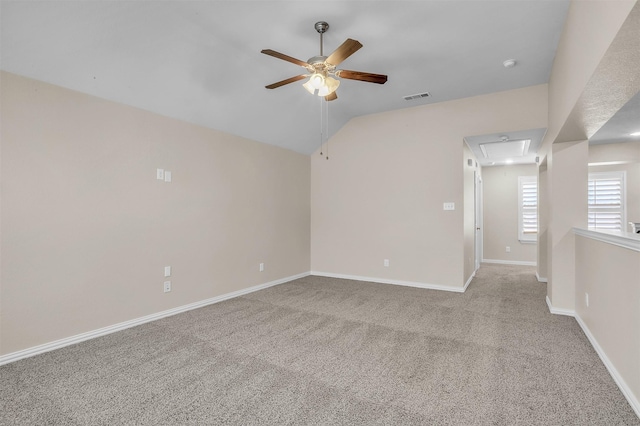 empty room featuring attic access, visible vents, baseboards, a ceiling fan, and lofted ceiling