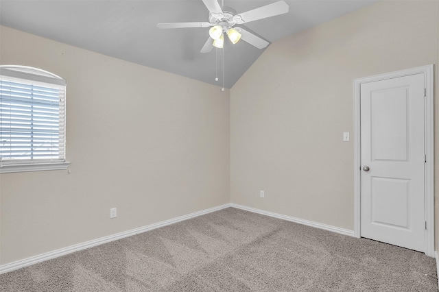 carpeted spare room featuring baseboards, vaulted ceiling, and a ceiling fan