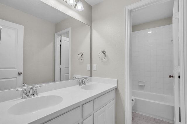 bathroom with toilet, double vanity, a sink, and tile patterned floors