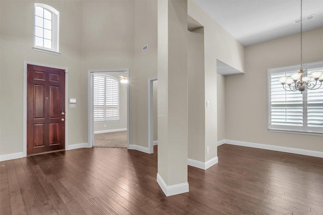 foyer entrance with dark wood-style floors, a chandelier, visible vents, and baseboards