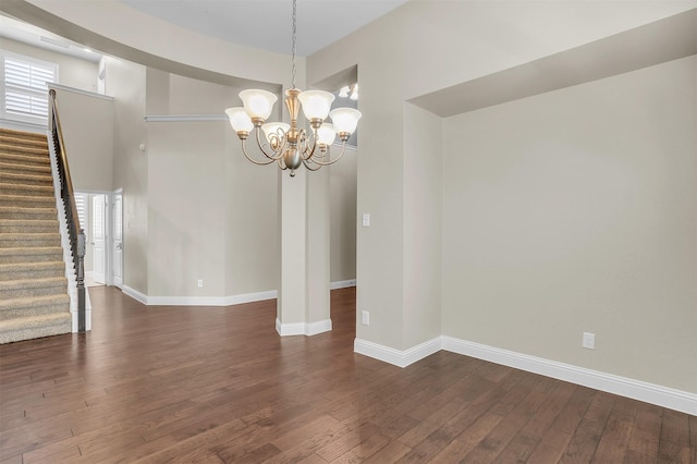 unfurnished dining area featuring baseboards, dark wood-style floors, a high ceiling, stairs, and a chandelier