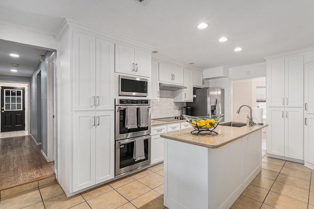 kitchen featuring appliances with stainless steel finishes, white cabinets, a sink, and light tile patterned flooring