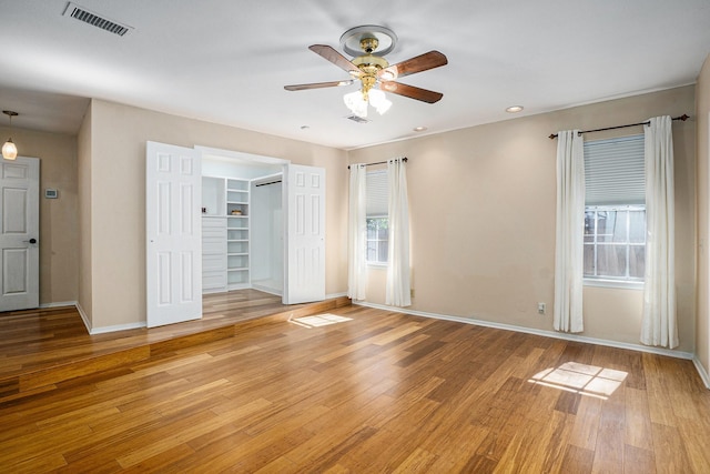 empty room with ceiling fan, light wood finished floors, visible vents, and baseboards