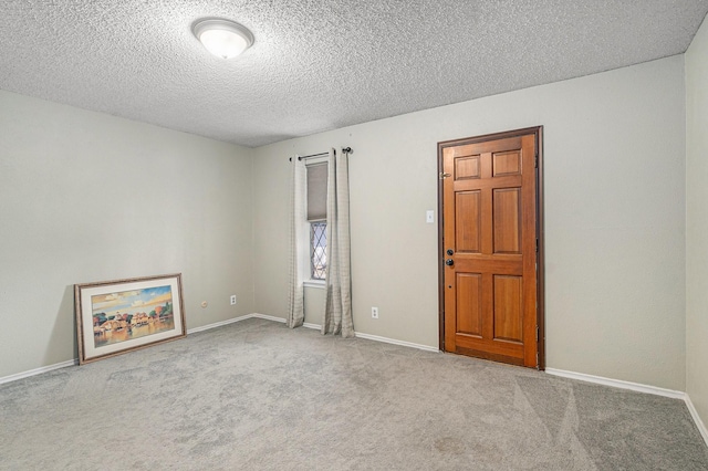 carpeted empty room featuring a textured ceiling and baseboards