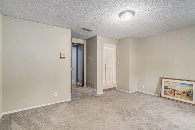 unfurnished room with baseboards, visible vents, a textured ceiling, and carpet flooring